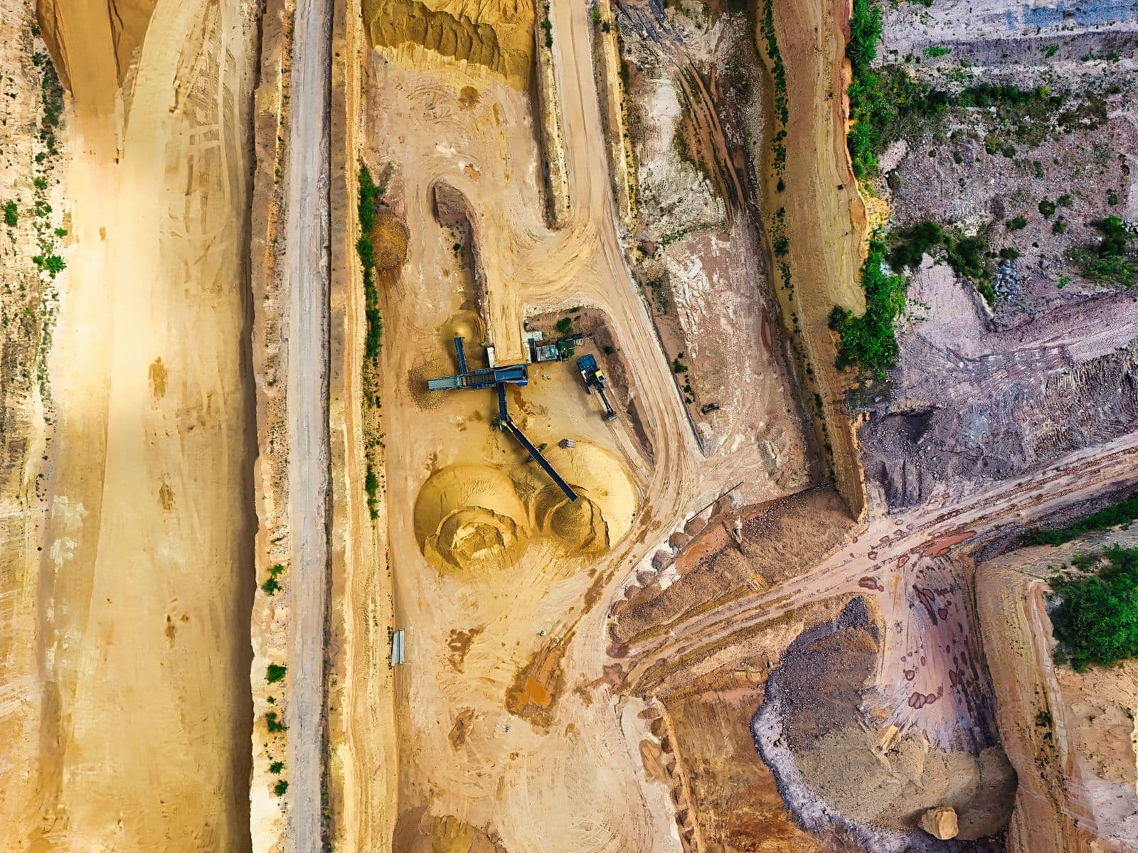Aerial view of an open-pit working face with haul roads and processing plant.