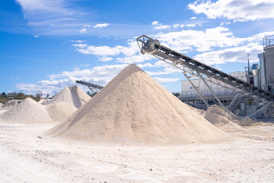A conveyor discharging onto a stockpile of bulk aggregate at a quarry.