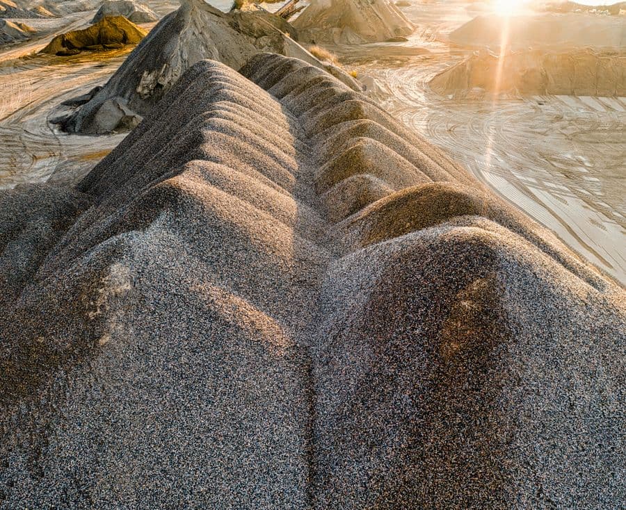 Ridged stockpiles of graded granular material at a processing yard.