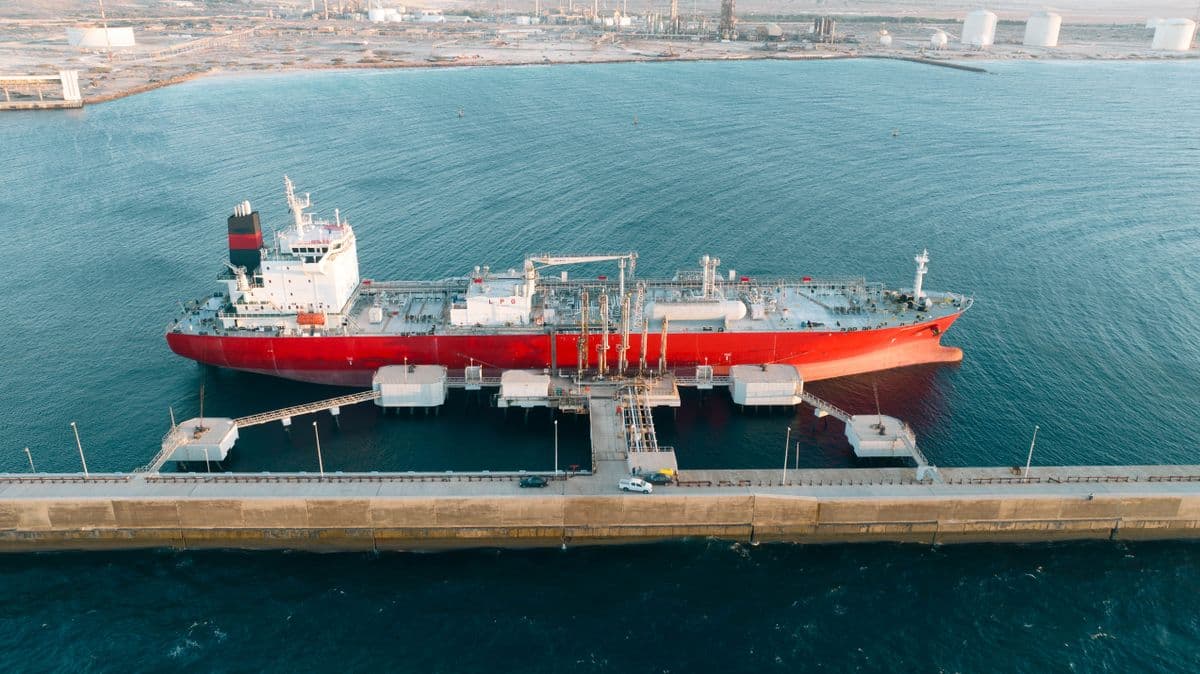 Aerial view of a tanker berthed at a loading jetty beside shoreside storage tanks.